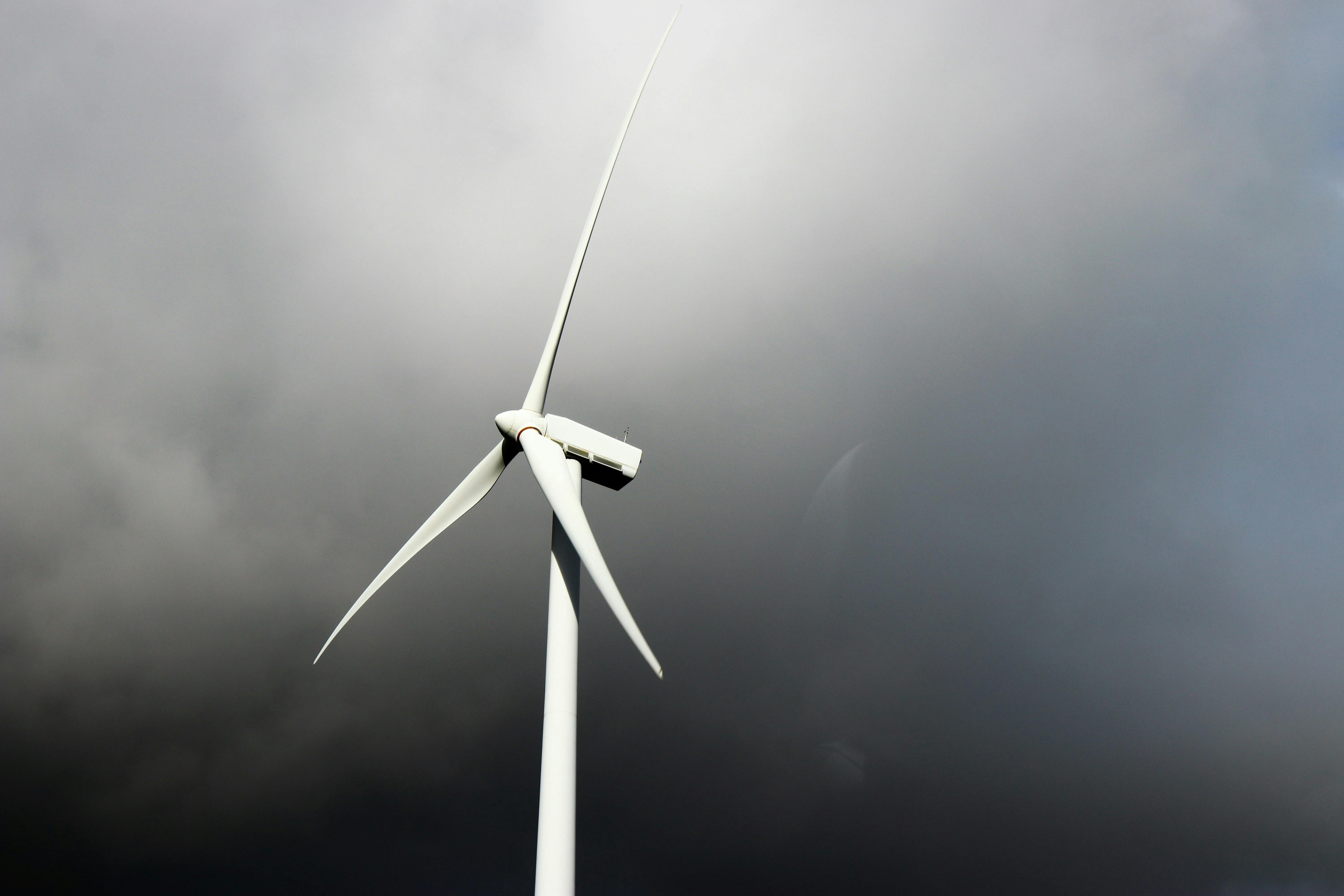 Wind turbine viewed from below against a cloudy sky.
